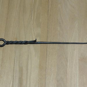 May include: A black metal fireplace poker with a twisted handle and a hook on the end.