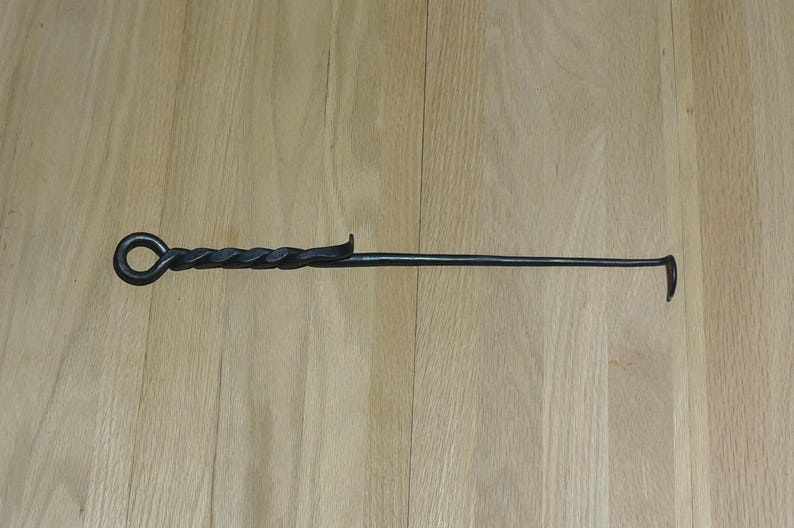 May include: A black metal fireplace poker with a twisted handle and a hook on the end.