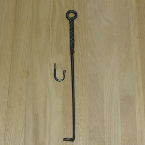 May include: A black metal fireplace tool with a twisted handle and a hook on the end. The tool is about 30 inches long.