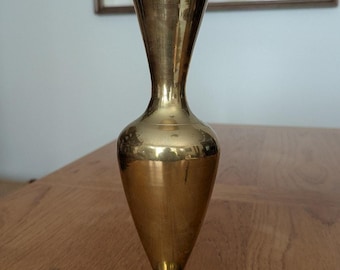May include: A brass vase with a flared top and a rounded body. The vase has a polished finish and sits on a circular base. The vase is approximately 8 inches tall.