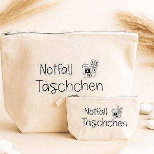 May include: Two beige canvas cosmetic bags with black text and illustrations. The larger bag has a zipper closure and the words "Notfall T&auml;schchen" and a pill bottle and pills illustration. The smaller bag has the same text and illustration.