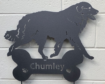 Könnte beinhalten: Schwarze Metall-Silhouette eines Hundes, der über einem knochenförmigen Schild läuft. Das Schild trägt den Namen "Chumley" mit Pfotenabdruck und Herz. Das Schild ist an einem Metallpfahl für den Garten befestigt.