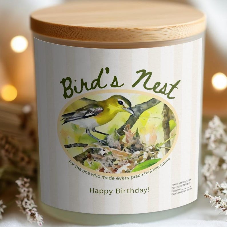 K&ouml;nnte beinhalten: Kerze in einem Glas mit Holzdeckel. Das Etikett tr&auml;gt die Aufschrift "Bird's Nest" mit einer Aquarellillustration eines gelben Vogels. Der Text "Happy Birthday!" und ein Zitat sind ebenfalls auf dem Etikett zu sehen.