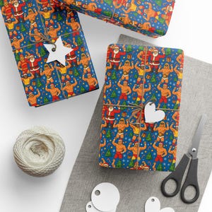 May include: Gift wrap featuring a repeating pattern of Santa Claus and muscular wrestlers on a blue background. The wrapped gifts are tied with twine and adorned with star and heart-shaped tags. A ball of twine and scissors are also visible.
