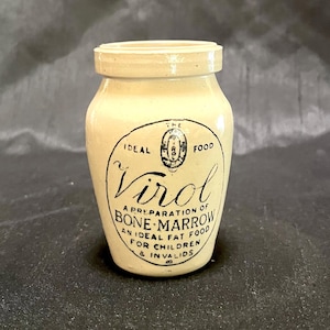 Może przedstawiać: Antyczny ceramiczny słoik z białą glazurą i czarnym nadrukiem. Słoik jest oznaczony etykietą "Virol, A preparation of Bone-Marrow, An Ideal Fat Food for Children & Invalids".