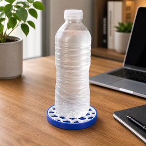 Puede incluir: Una botella de agua de plástico transparente, con tapa blanca, se encuentra sobre un posavasos azul y blanco con diseño de panal. La botella está sobre un escritorio de madera, con un portátil y un cuaderno en el fondo.