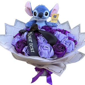 Op de afbeelding: Een boeket van paarse en lavendelkleurige rozen van lint, bekroond met een Stitch-knuffel. Het boeket is verpakt in decoratief papier en vastgebonden met een paars lint. Een zwart lint met de tekst "Your text" is ook inbegrepen.