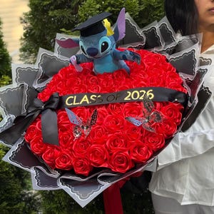 May include: A graduation bouquet featuring a plush Stitch toy wearing a graduation cap, set atop a bed of red roses. The bouquet includes a black ribbon with "CLASS OF 2026" and decorative butterflies. The bouquet is wrapped in black and white paper.