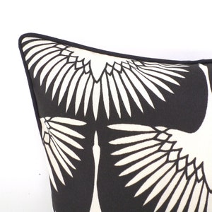 May include: Close-up of a black and white decorative pillow. The pillow features a repeating pattern of stylized white birds against a black background. The pillow has a black border.