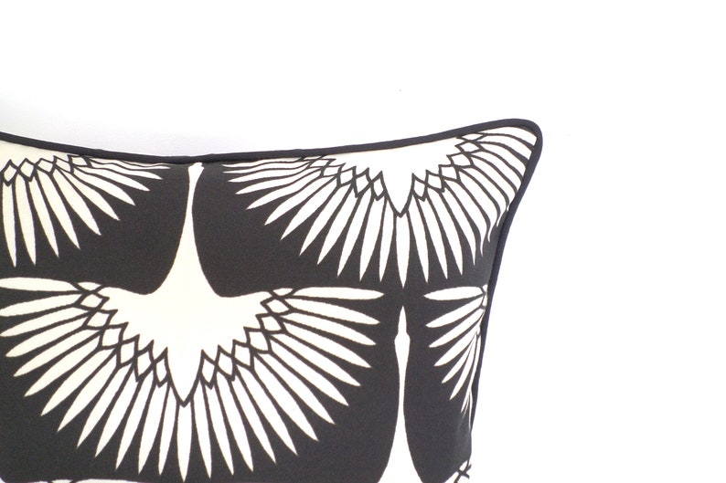 May include: Decorative pillow with a black and white crane design. The pillow features a repeating pattern of stylized cranes with outstretched wings against a black background. The pillow has a black border.