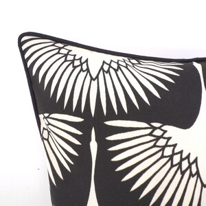 May include: Close-up of a black and white decorative pillow. The pillow features a repeating pattern of stylized white birds against a black background. The pillow has a black border.