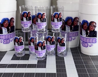 Può includere: Una collezione di bicchieri in schiuma bianchi e bicchierini da shot trasparenti, ognuno con un adesivo di due persone e il testo viola "FINEEEE 29". I bicchieri sono disposti in gruppo, mostrando lo stesso design grafico sulle superfici frontali.