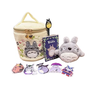 May include: A collection of Studio Ghibli's Totoro-themed merchandise. Includes a cream-colored cosmetic bag with embroidered Totoro, a plush Totoro, stickers, a pen, and a small book titled "Totoro".