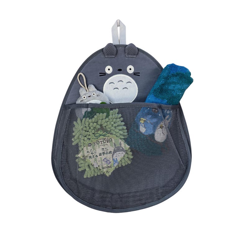 Puede incluir: Un organizador colgante gris con tem&aacute;tica de Totoro con un bolsillo de malla. El organizador presenta una cara y orejas de peluche de Totoro en la parte superior, con un peque&ntilde;o peluche y otros art&iacute;culos visibles dentro del bolsillo. Tambi&eacute;n es visible una toalla azul.
