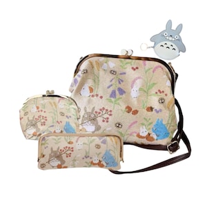 May include: A set of beige fabric bags with a floral and cartoon character design. The set includes a purse, a coin purse, a pencil case, and a small keychain. The bags have brown straps and metal clasps.