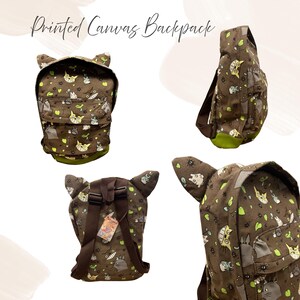 May include: Brown canvas backpack featuring a repeating pattern of cartoon characters and green detailing. The backpack has a unique design with cat-like ears and a green base. The text "Printed Canvas Backpack" is at the top.