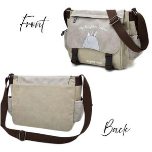 May include: A beige messenger bag with a brown shoulder strap and accents. The front flap features a gray illustration of Totoro with the text "My Neighbor Totoro" and "Neighbor Totoro". The bag has two black buckles.