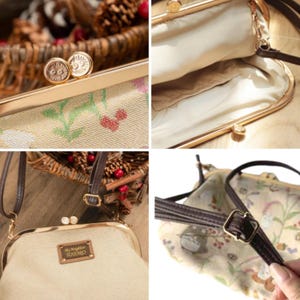 May include: A beige handbag with a floral pattern and a gold-colored clasp. The bag has a brown strap and a rectangular tag that reads "My Neighbor TOTORO". The bag is open, revealing a beige interior.
