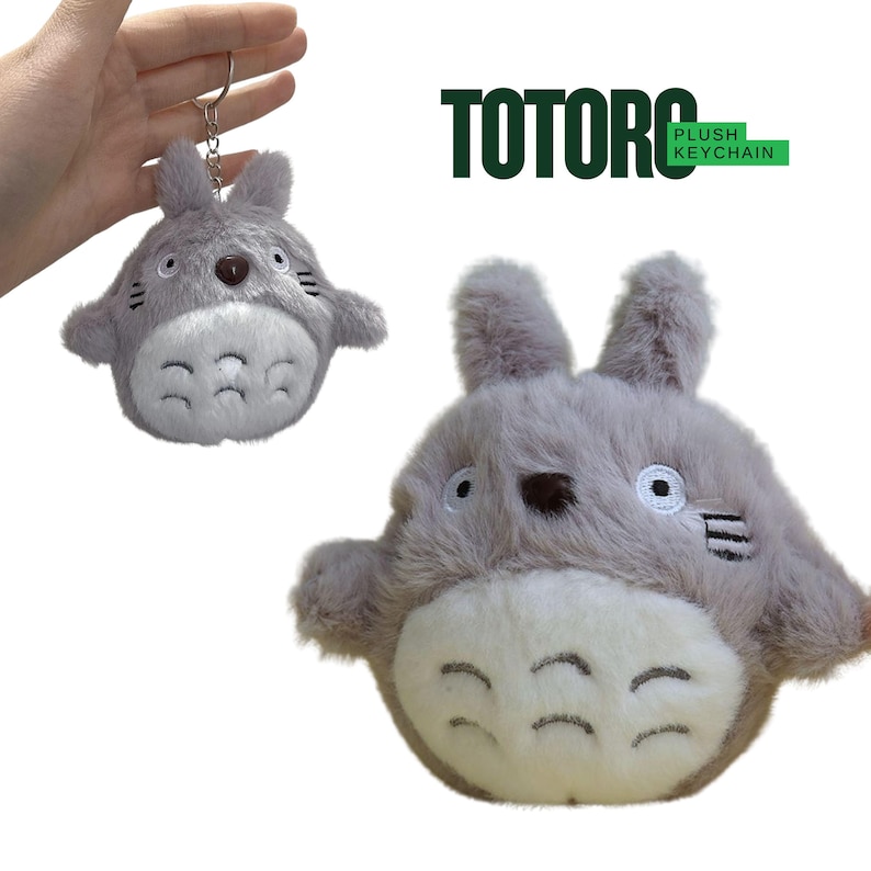 May include: A gray plush Totoro keychain with a silver keyring. The plush toy has a white belly, black markings, and a brown nose. The image also shows a larger plush Totoro with the text "TOTORO PLUSH KEYCHAIN".