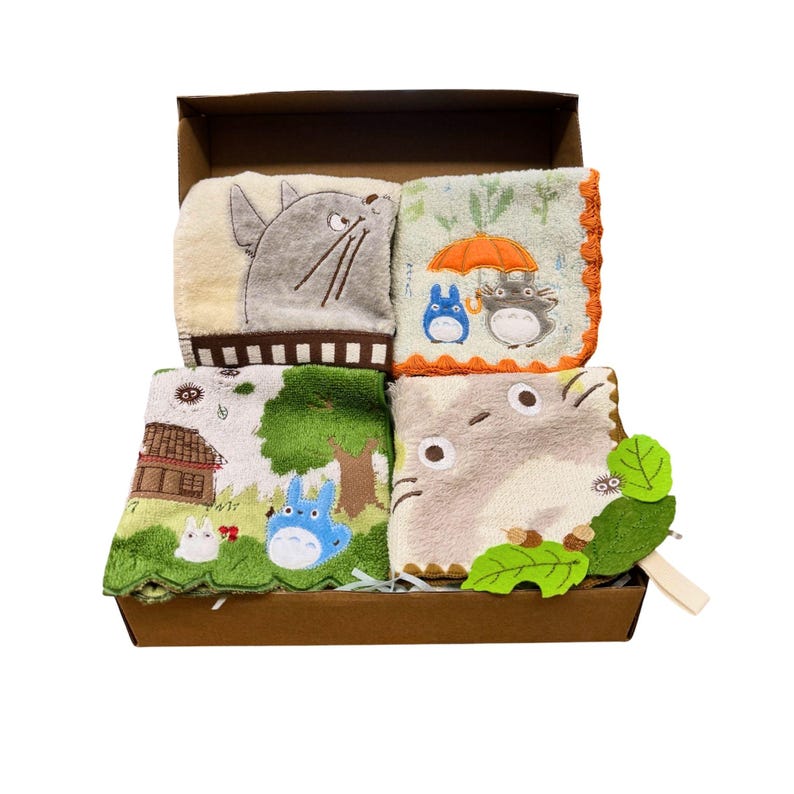 May include: A set of four embroidered washcloths featuring characters from a popular animated film, presented in a brown box. The washcloths showcase various scenes with the characters in different settings, with a variety of colors including beige, green, and blue.