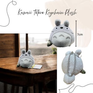 K&ouml;nnte beinhalten: Ein grauer Totoro-Schl&uuml;sselanh&auml;nger aus Pl&uuml;sch, ca. 7 cm hoch, mit einer silbernen Kette. Der Schl&uuml;sselanh&auml;nger hat einen runden K&ouml;rper, kleine Ohren und einen wei&szlig;en Bauch. Der Text "Kawaii Totoro Keychain Plush" steht oben.