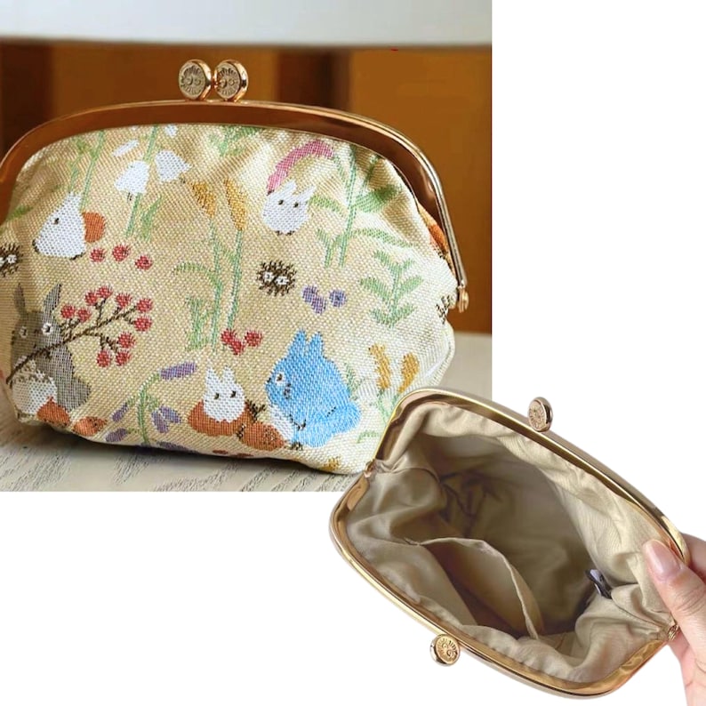 May include: A beige fabric coin purse with a gold-colored metal frame and clasp. The purse features a colorful embroidered design of cartoon characters, flowers, and plants. The interior of the purse is a light beige color.