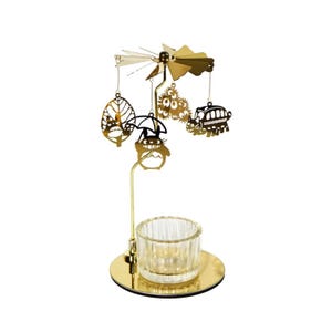 May include: A gold-colored candle holder with a rotating top featuring cut-out designs of a leaf, a character with an umbrella, a floral design, and a bus. The base holds a clear glass candle cup.