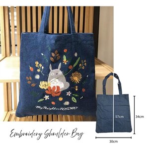 May include: A blue denim tote bag with embroidered floral and Totoro character design. The bag measures 34cm high, 30cm wide, and 57cm in handle length. The text "My Neighbor TOTORO" is embroidered on the bag.