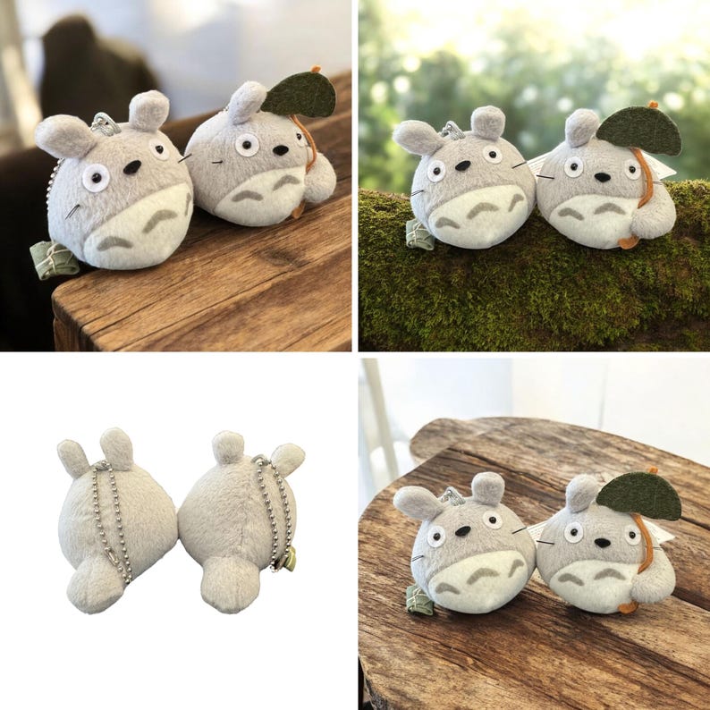 K&ouml;nnte beinhalten: Zwei flauschige, graue Totoro-Schl&uuml;sselanh&auml;nger mit wei&szlig;en B&auml;uchen, schwarzen Augen und kleinen Ohren. Ein Schl&uuml;sselanh&auml;nger hat ein gr&uuml;nes Blatt als Zubeh&ouml;r. Die Schl&uuml;sselanh&auml;nger befinden sich auf einer Holzoberfl&auml;che.