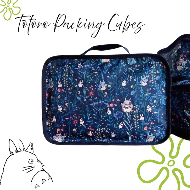 Puede incluir: Cubo de embalaje azul oscuro con un estampado floral y Totoro. El cubo tiene un borde negro y un asa negra. El texto "Totoro Packing Cubes" est&aacute; escrito en cursiva. Una ilustraci&oacute;n de Totoro est&aacute; en la esquina.