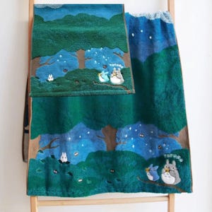May include: Two green and blue plush towels with a forest scene featuring cartoon characters. The towels have a forest design with trees, stars, and cartoon characters. The word "TOTORO" is visible on one of the towels.