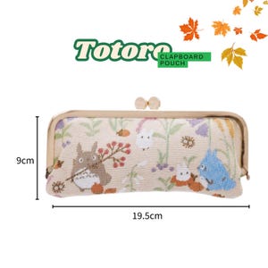 May include: A beige claptboard pouch with a gold clasp, featuring a Totoro design. The pouch is 19.5cm long and 9cm high. The design includes illustrations of Totoro and other characters, with floral and leaf accents.