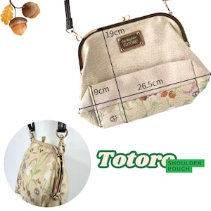 May include: Beige shoulder pouch with a floral pattern and a metal clasp. The bag measures 19 cm high, 26.5 cm wide, and 9 cm deep. The text "My Neighbor Totoro" is on a small plaque. The bag has a black strap.