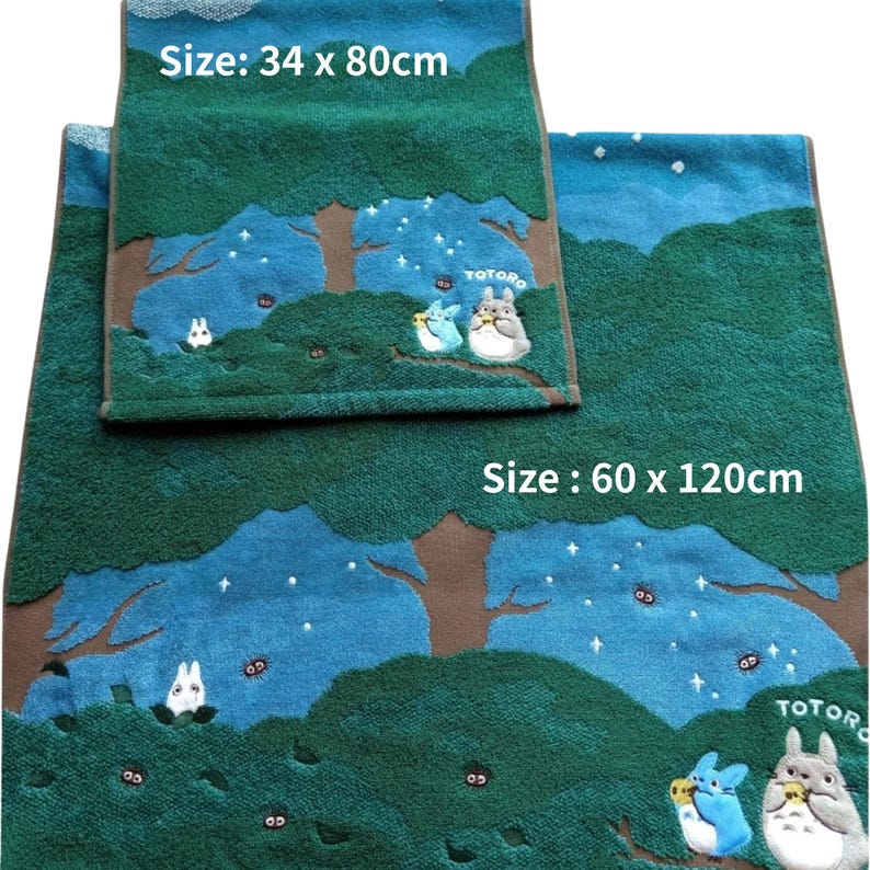 May include: Two green and blue bath towels with a forest design and Totoro characters. The larger towel measures 23.6 x 47.2 inches, and the smaller towel is 13.4 x 31.5 inches. The towels have a brown border and white text.