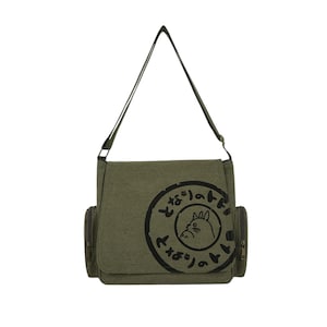 May include: Olive green messenger bag with a black graphic of a cat inside a circle with Japanese text. The bag has a flap closure, two side pockets, and an adjustable shoulder strap.