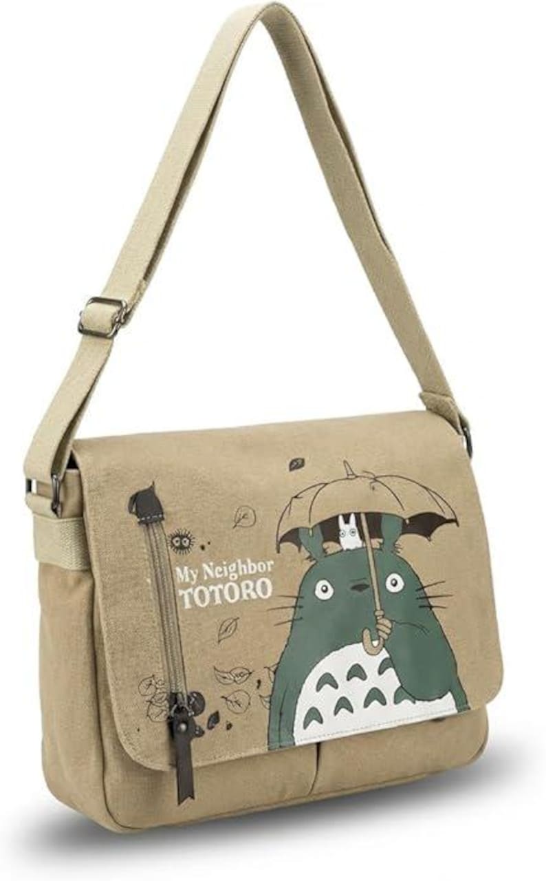 May include: Beige messenger bag featuring a green and white cartoon character holding an umbrella. The bag has a long, adjustable strap and a flap closure. The text "My Neighbor Totoro" is printed on the front.
