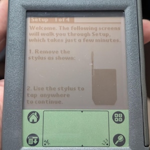 Puede incluir: Una taza de cerámica blanca con un asa negra y el texto "But First, Coffee" en negrita negra. La taza está sobre un fondo borroso, sugiriendo un ambiente acogedor. La taza mide aproximadamente 10 cm de altura.