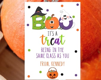 May include: Two orange pumpkins in a wooden crate with a Halloween-themed gift tag. The tag reads "Boo, It's a treat being in the same class as you, From Kennedy" with cartoon graphics of a witch hat, pumpkin, and ghost.