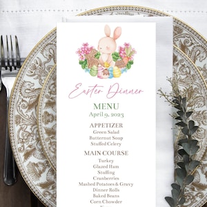 May include: An Easter dinner menu card with a bunny and eggs illustration, set on a decorative plate with cutlery, a napkin, and foliage. The menu lists appetizers, main courses, and desserts for April 9, 2023.