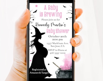 Puede incluir: Un teléfono inteligente muestra una invitación a un baby shower. La invitación presenta una silueta de una mujer embarazada con un sombrero de bruja y el texto "A Baby is Brewing". Acentos rosas y gráficos temáticos de Halloween completan el diseño.