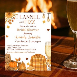 Puede incluir: Una copa de champán llena de una bebida dorada se encuentra sobre una manta a cuadros junto a una invitación a una despedida de soltera. La invitación presenta el texto "Flannel and Fizz" y los detalles del evento.
