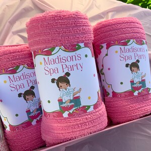 K&ouml;nnte beinhalten: Drei rosa Handt&uuml;cher in einer Geschenkbox mit personalisierten Etiketten, auf denen "Madison's Spa Party" steht. Jedes Etikett zeigt ein Cartoon-M&auml;dchen in einem Bademantel und einem Blumendesign.
