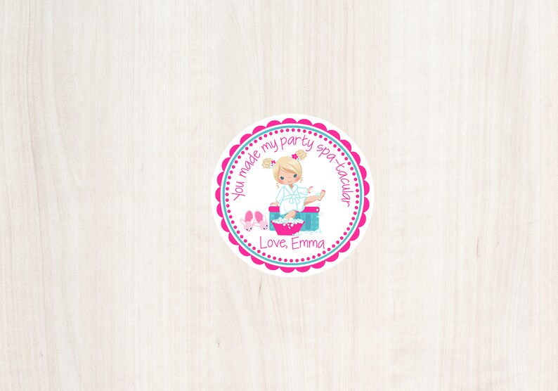 May include: Round pink and blue favor tag with a white background. The tag features a cartoon girl in a white robe with blonde hair, sitting in a foot bath. The text reads "You made my party spa-tacular. Love, Emma."