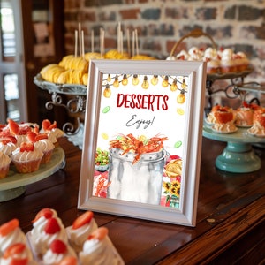 Könnte beinhalten: Ein weiß gerahmtes Schild mit dem Text "DESSERTS Enjoy!" in Rot und Schwarz. Das Schild zeigt eine Aquarell-Illustration eines Topfes mit Krebsen, Zitronen und Gurken.