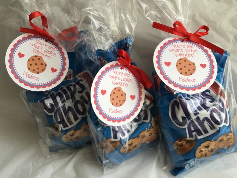 May include: Three clear plastic bags filled with Chips Ahoy chocolate chip cookies, each tied with a red ribbon and a round tag that reads "You're one smart cookie, Valentine!" with a chocolate chip cookie graphic and the name "Madison".