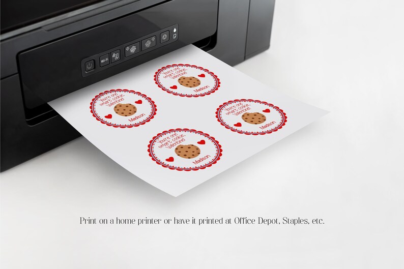 May include: A sheet of paper with four round stickers printed on it. The stickers are red and white with a chocolate chip cookie and the text "You are one sweet cookie, Valentine". The stickers are being printed from a black and white printer.