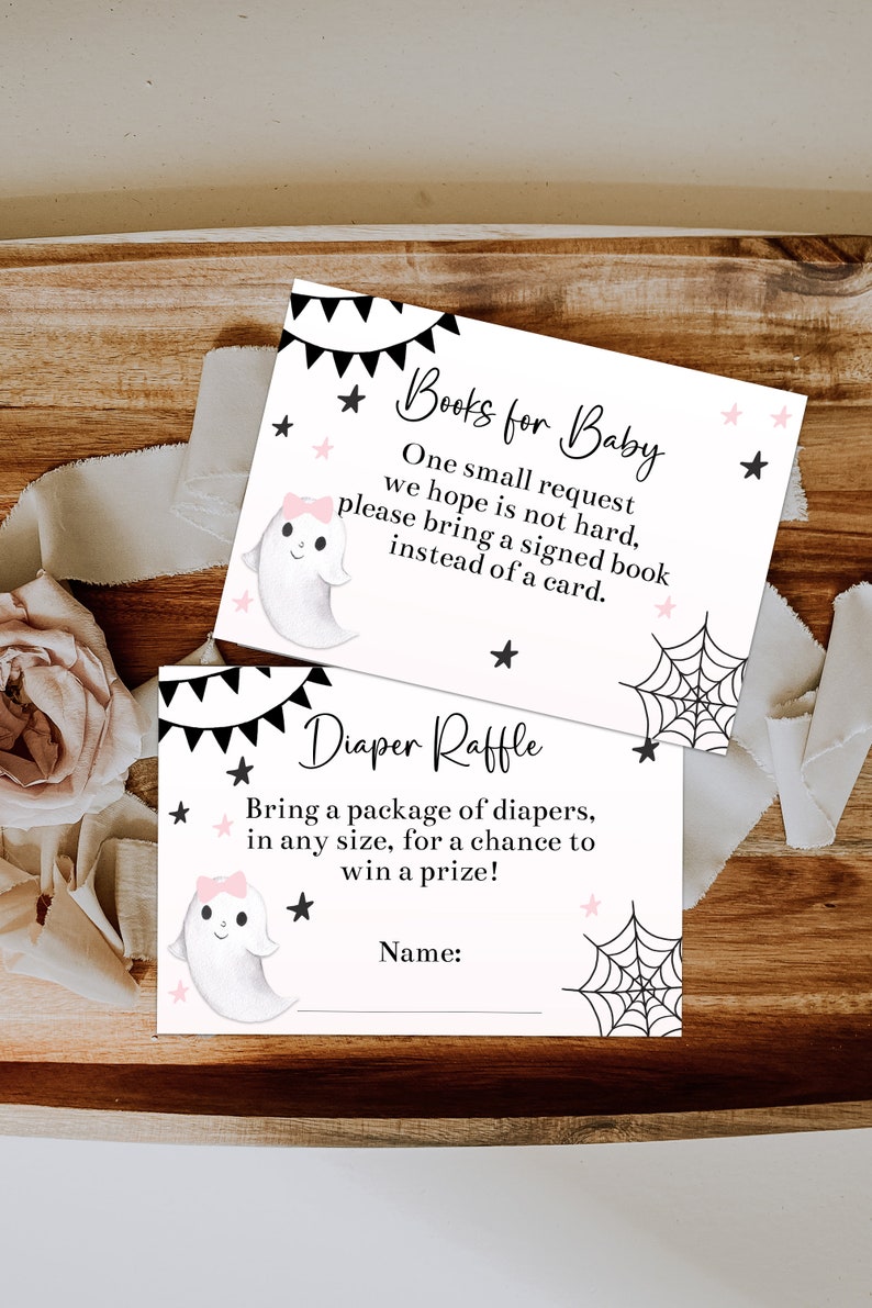 May include: Two baby shower cards with a Halloween theme. One card reads "Books for Baby" and the other reads "Diaper Raffle". Both cards feature a cute ghost illustration, black and pink accents, and text.