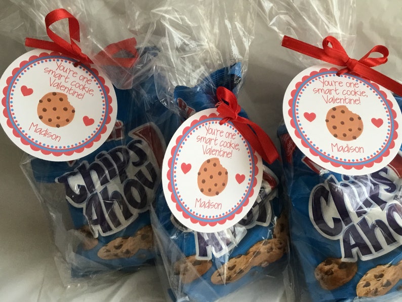 May include: Three bags of Chips Ahoy chocolate chip cookies with a red ribbon and a round Valentine's Day tag attached to each bag. The tag says "You're one smart cookie, Valentine!" with a chocolate chip cookie graphic and the name "Madison".