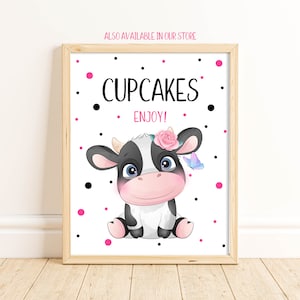May include: A white sign with black polka dots and pink polka dots. The sign says "Cupcakes Enjoy!" and features a cartoon black and white cow with a pink flower and a blue butterfly.