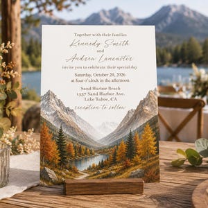 Może przedstawiać: Prostokątne zaproszenie ślubne z nadrukowanym krajobrazem gór, jeziora i jesiennych drzew. Tekst brzmi: Together with their families, Kennedy Smith and Andrew Lancaster, invite you to celebrate their special day, Saturday, October 20, 2026, at four o'clock in the afternoon, Sand Harbor Beach, 1557 Sand Harbor Ave, Lake Tahoe, CA, reception to follow.